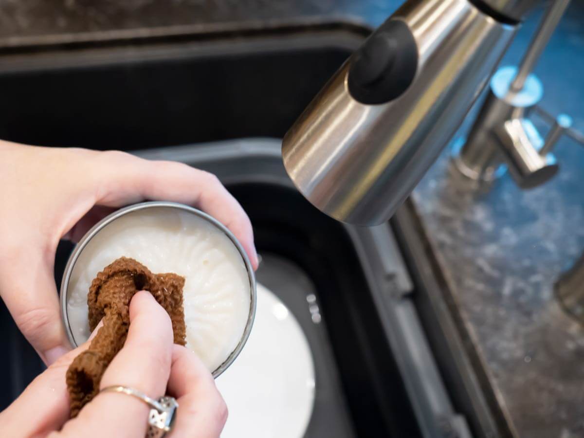 woman washing dishes at RV sink with solid dish soap and rag