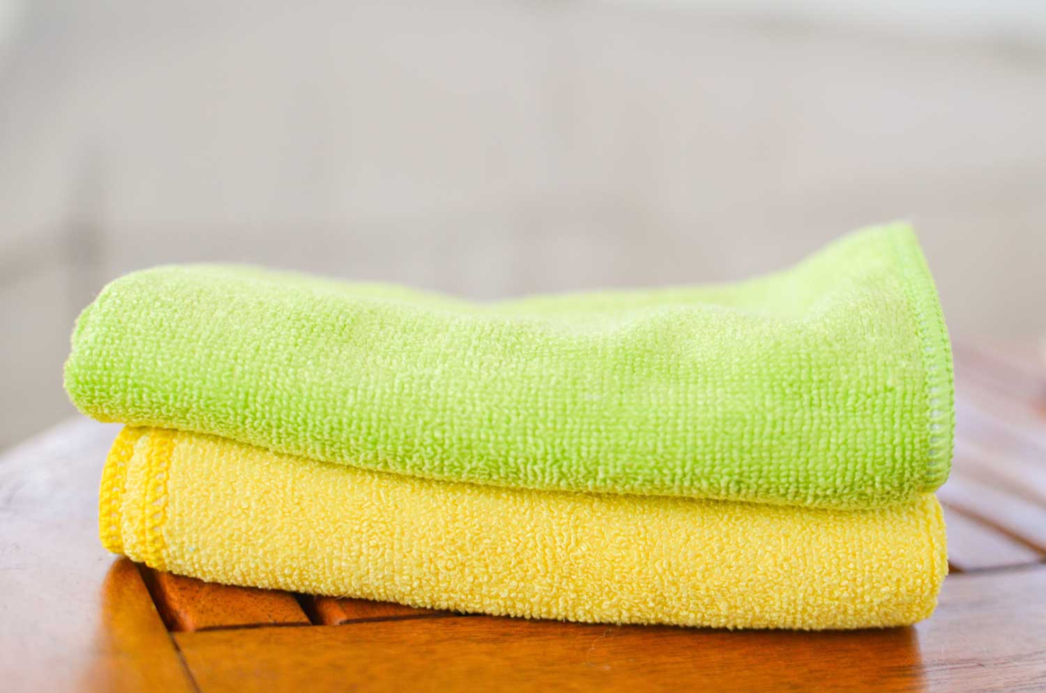 Two eco-cloth microfiber towels folded and stacked on a table.