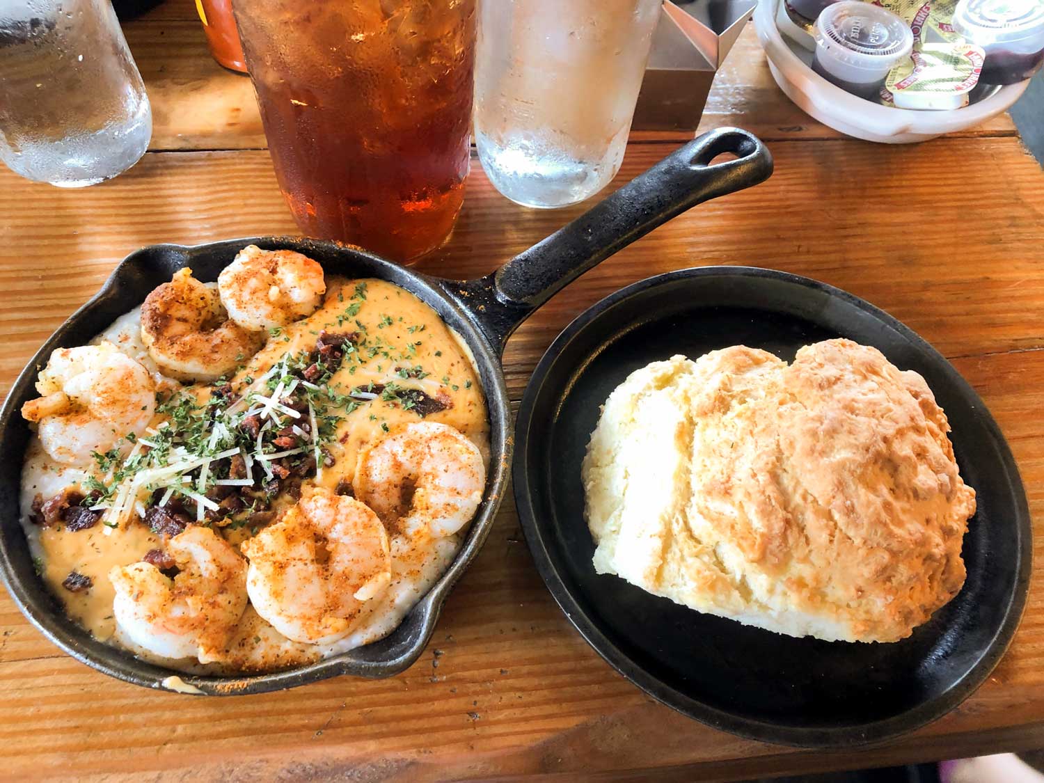 iron skillet with shrimp and grits and second iron skillet with large biscuit