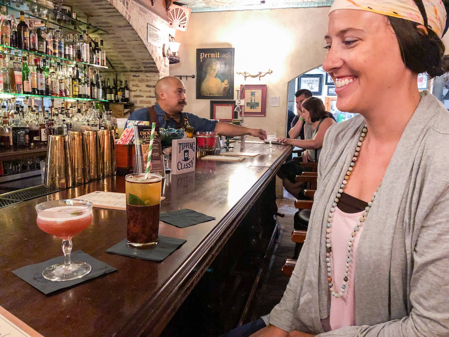 woman sitting at the bar at speak easy with fresh cocktails 