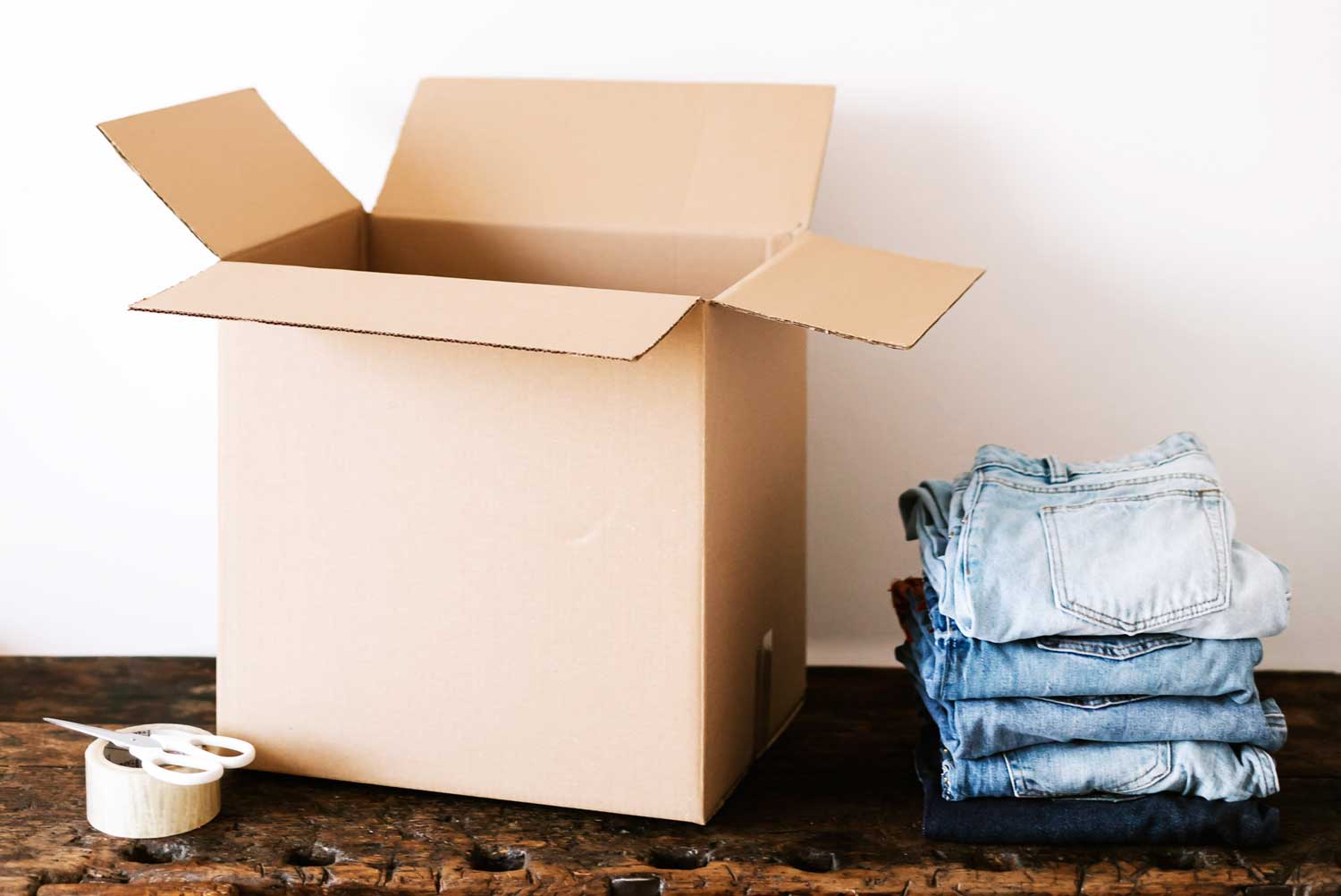 Empty box on table with clothes to be decluttered