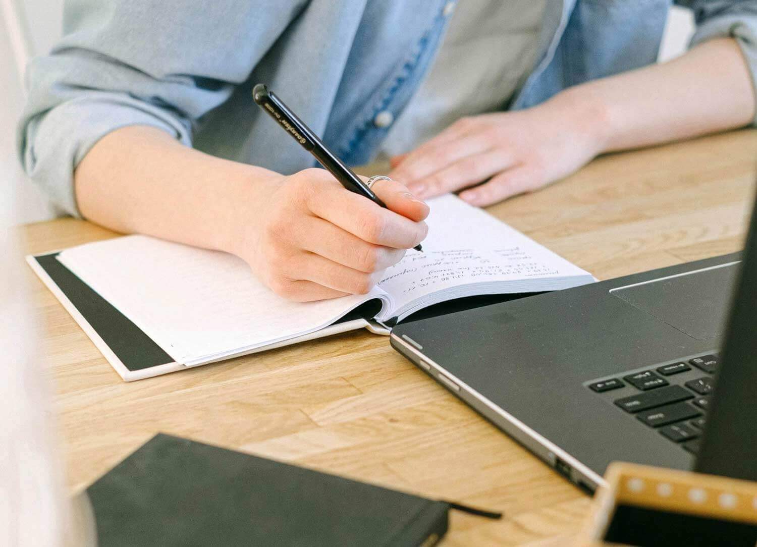 Someone sitting at a desk writing in a notebook