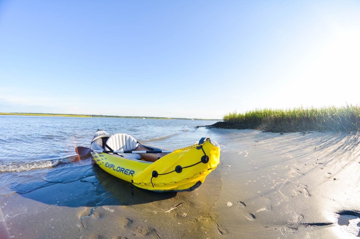 inflatable kayak on beach in front of grass dunes