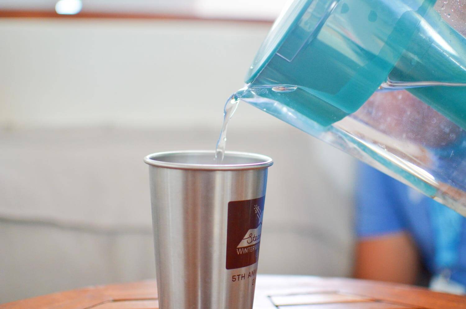 Water being poured from a filtered pitcher to a cup