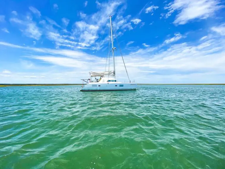 sailboat anchored on green water with blue sky behind