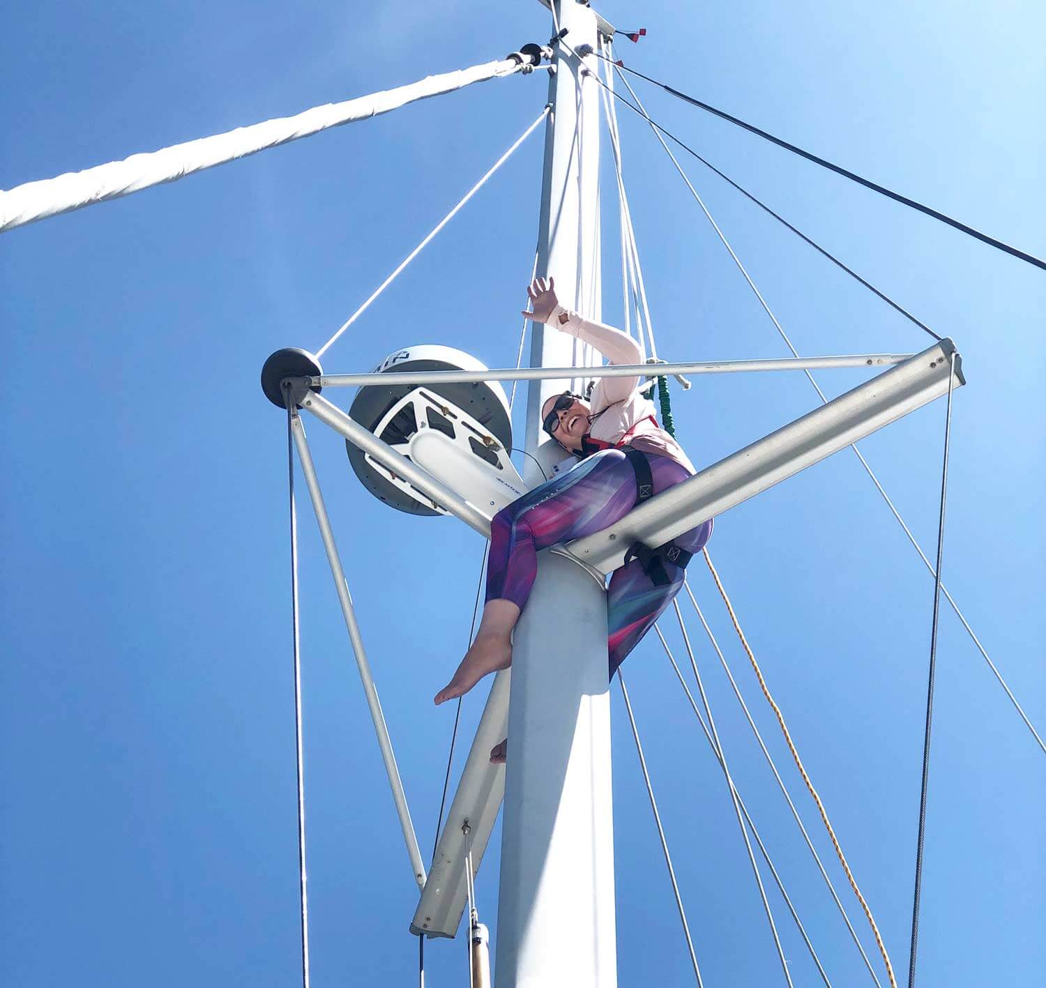 woman crew member on top of sailboat mast