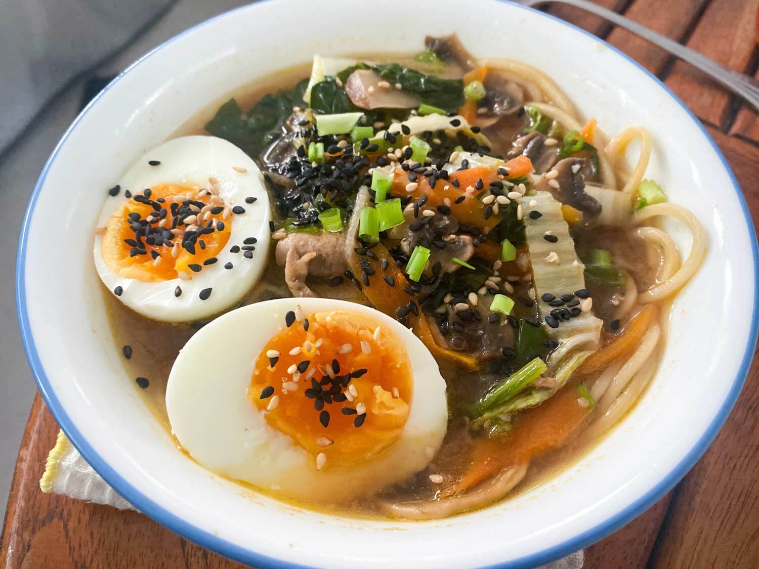 ramen meal in bowl topped with green onion, sesame seeds, and poached egg