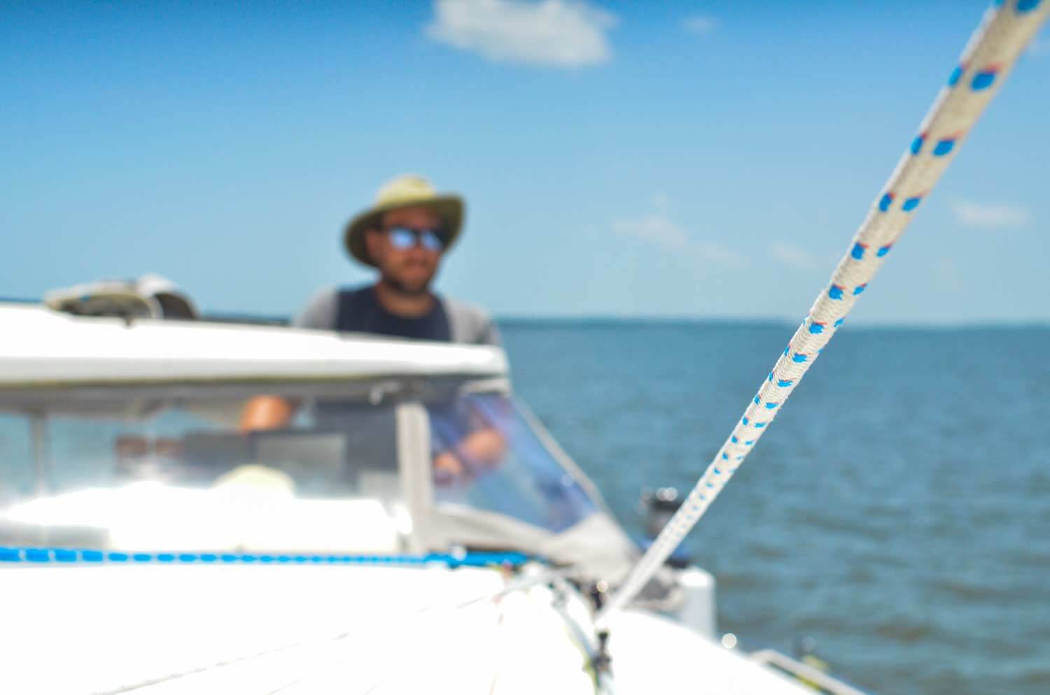 Sailboat jib line with captain at helm in background