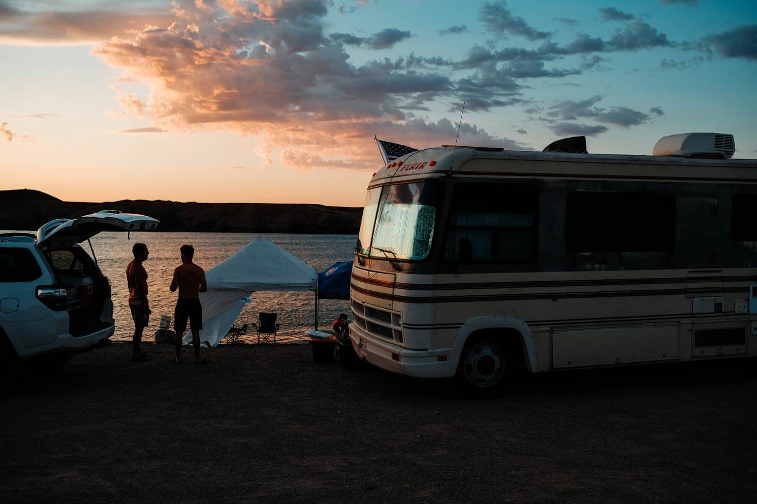 Motorhome parked by a lake at dusk