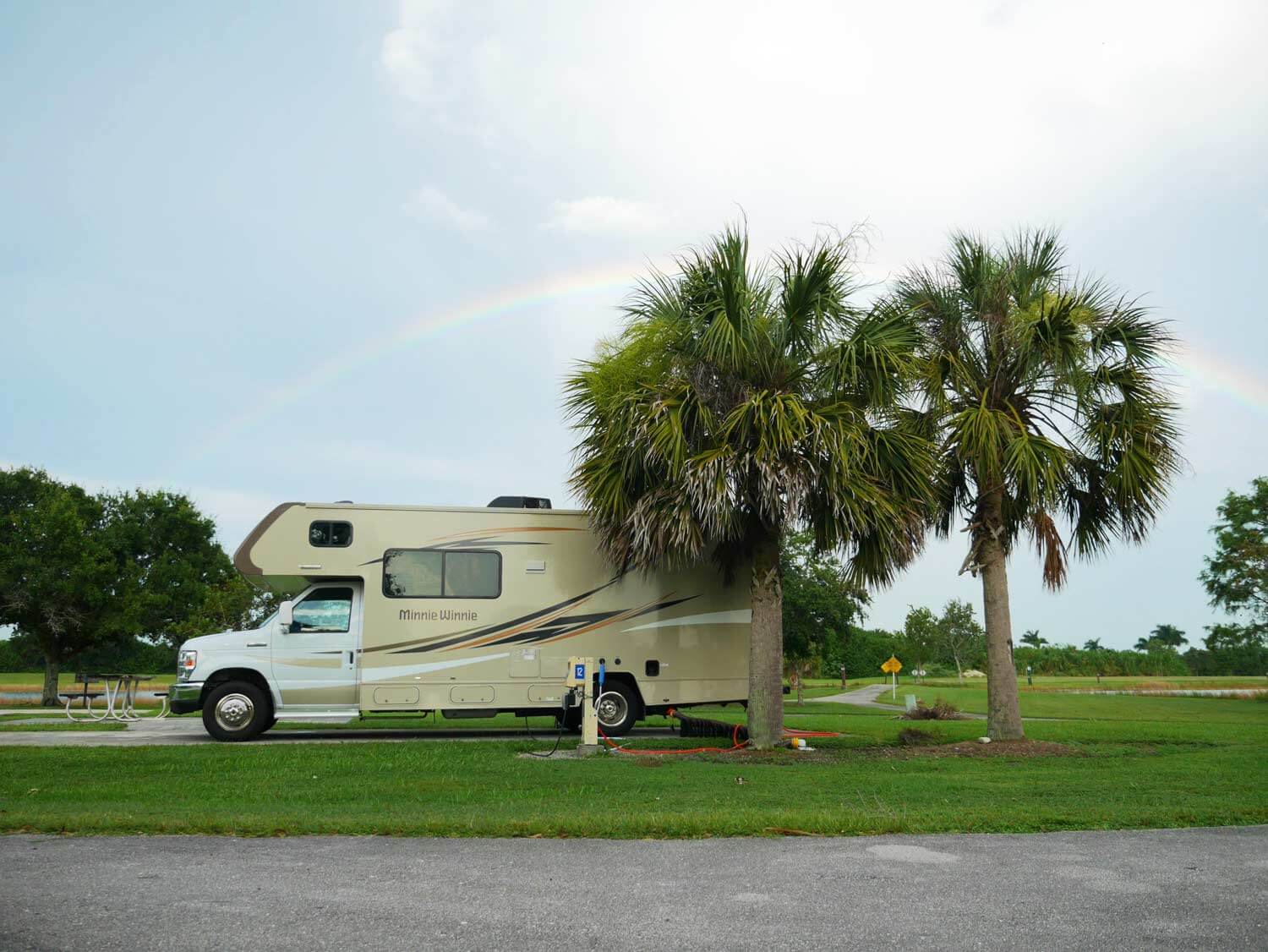 Motorhome parked in a campsite with rainbow in the background