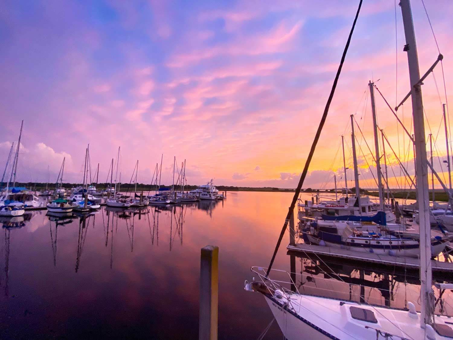 Marina with sailboats at sunset with purple skies