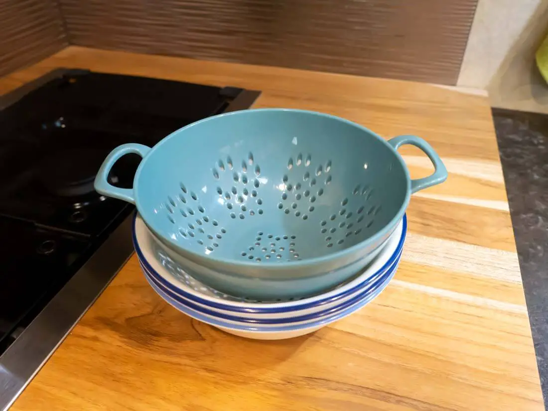 small colander stacked on top of bowls on counter top