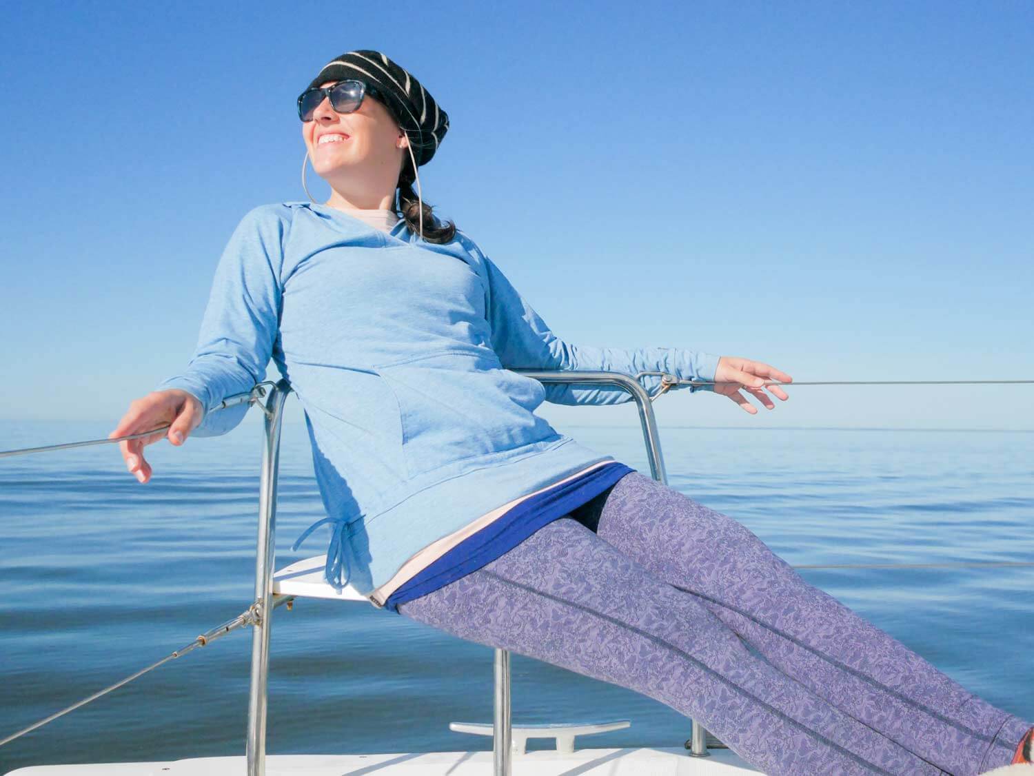 woman on dolphin seat of catamaran wearing cool weather sailing clothes