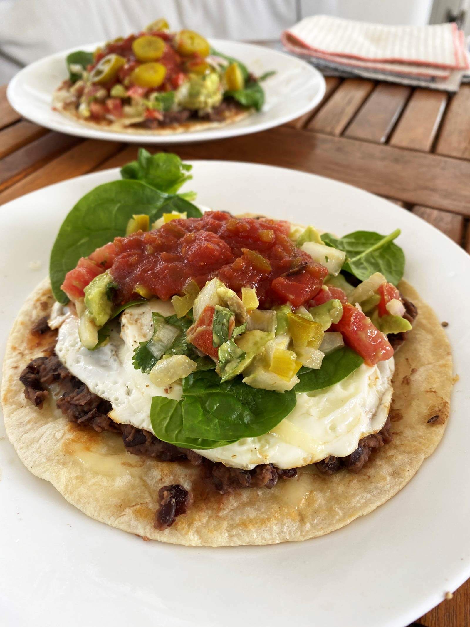 huevos rancheros with bean, eggs, veggies, and salsa on top