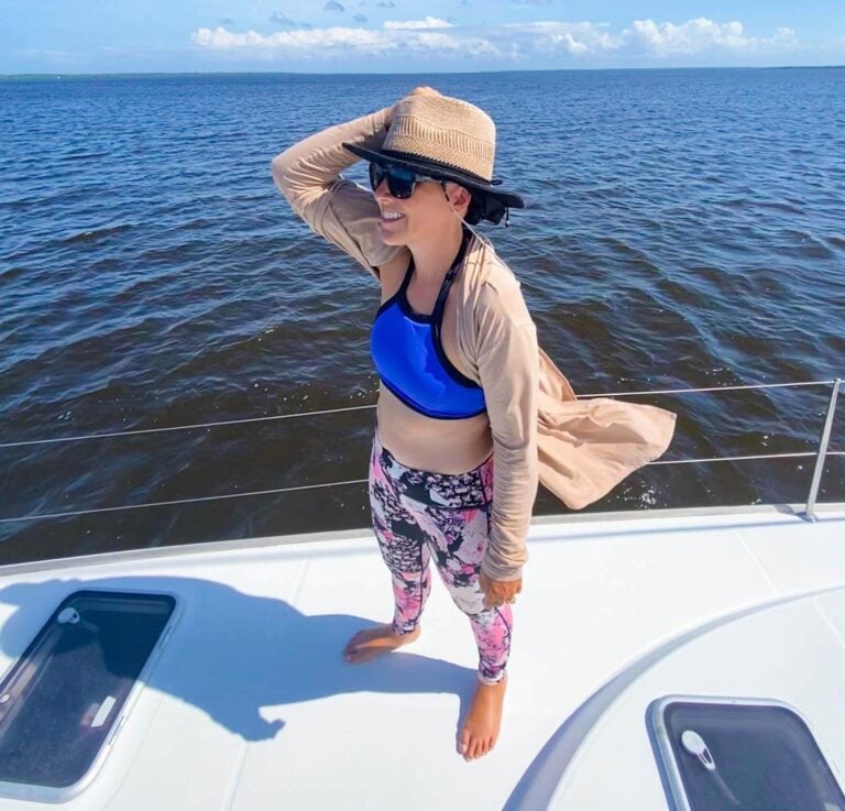 woman standing on bow of catamaran in sailing clothes