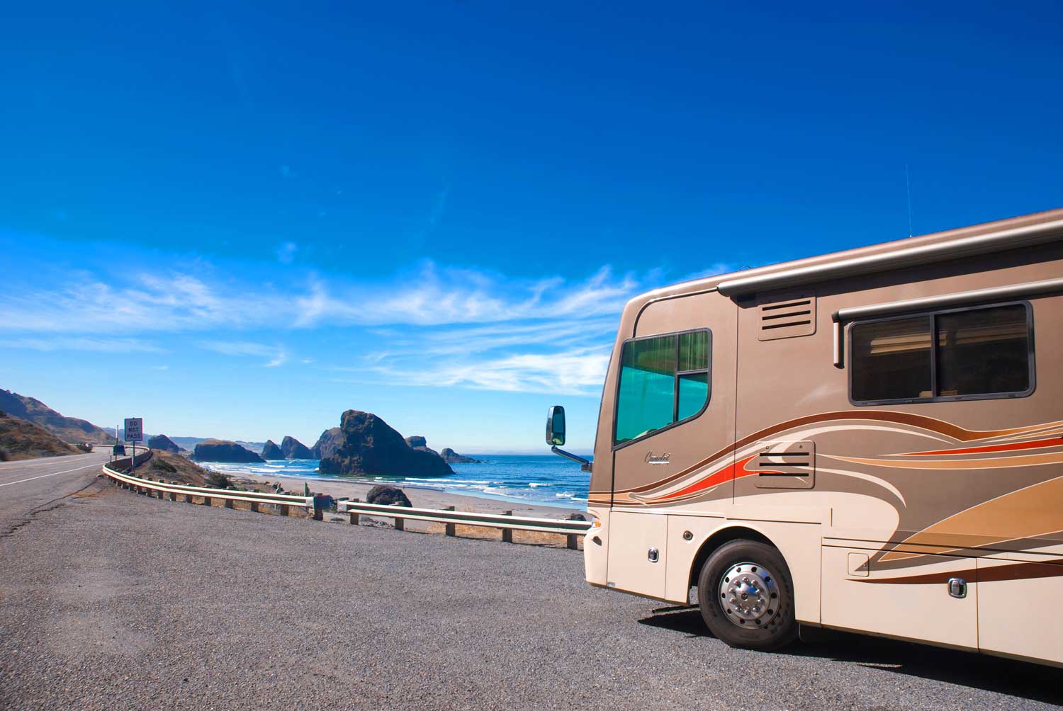 RV motorhome pulled off on the side of the road beside the ocean.