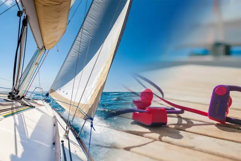 Sailboat on the water with jib out and headphones lying on a cockpit table.