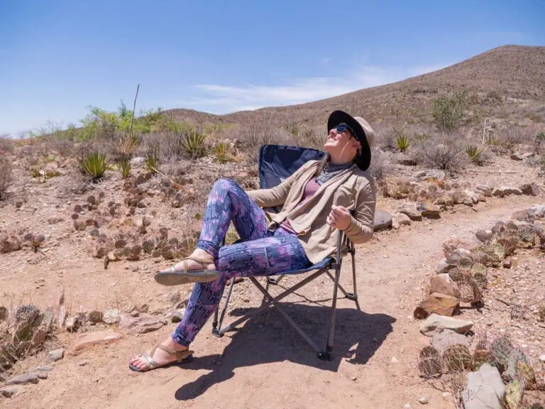 woman sitting in a camping chair in the desert wearing comfortable camping clothes