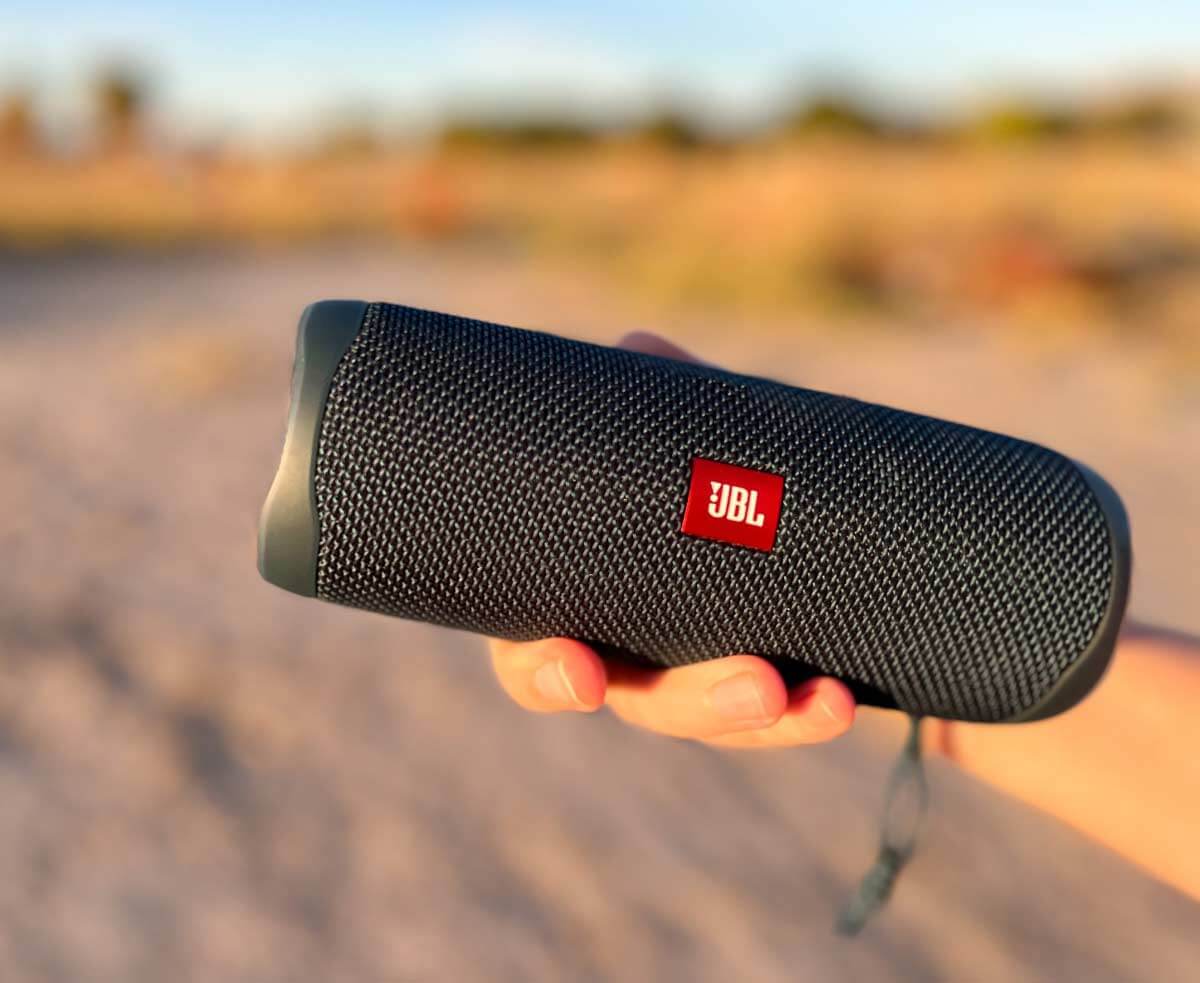 Hand holding a portable bluetooth speaker to show the small size of the item. 