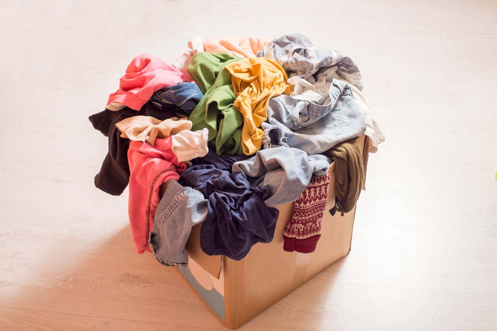 cardboard box full of discarded clothes needing motivation for decluttering