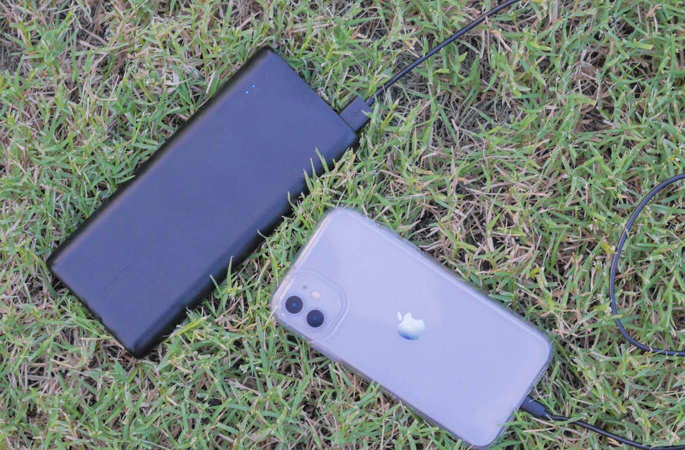 portable battery pack attached to iphone in the grass