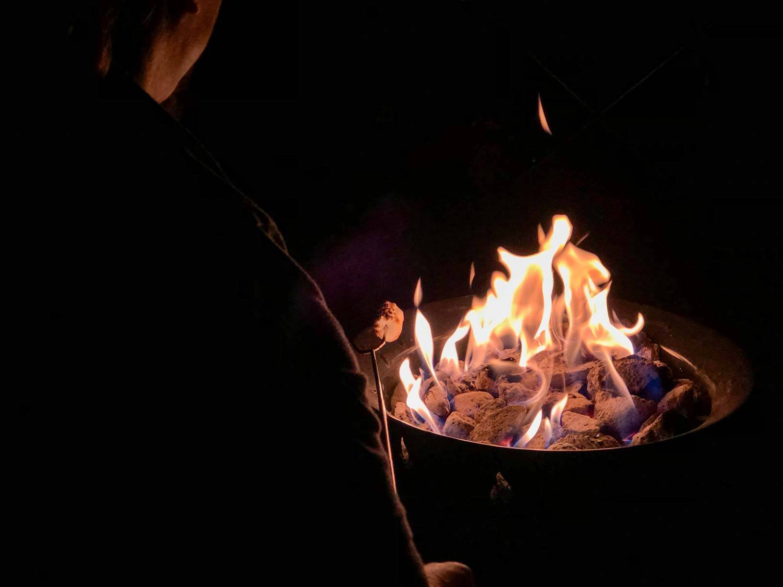 Propane fire pit with a fire at an RV campsite.