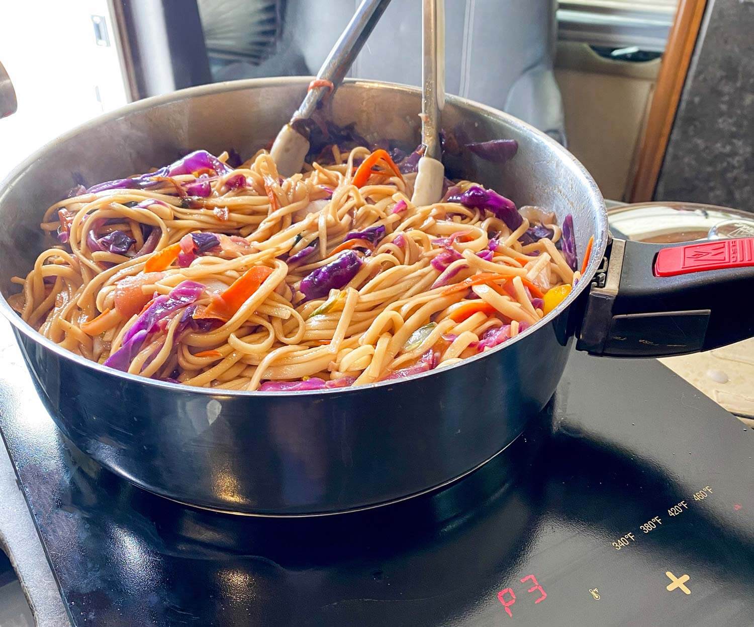 Magma skillet with stir-fried noodles on an induction plate in an RV kitchen.