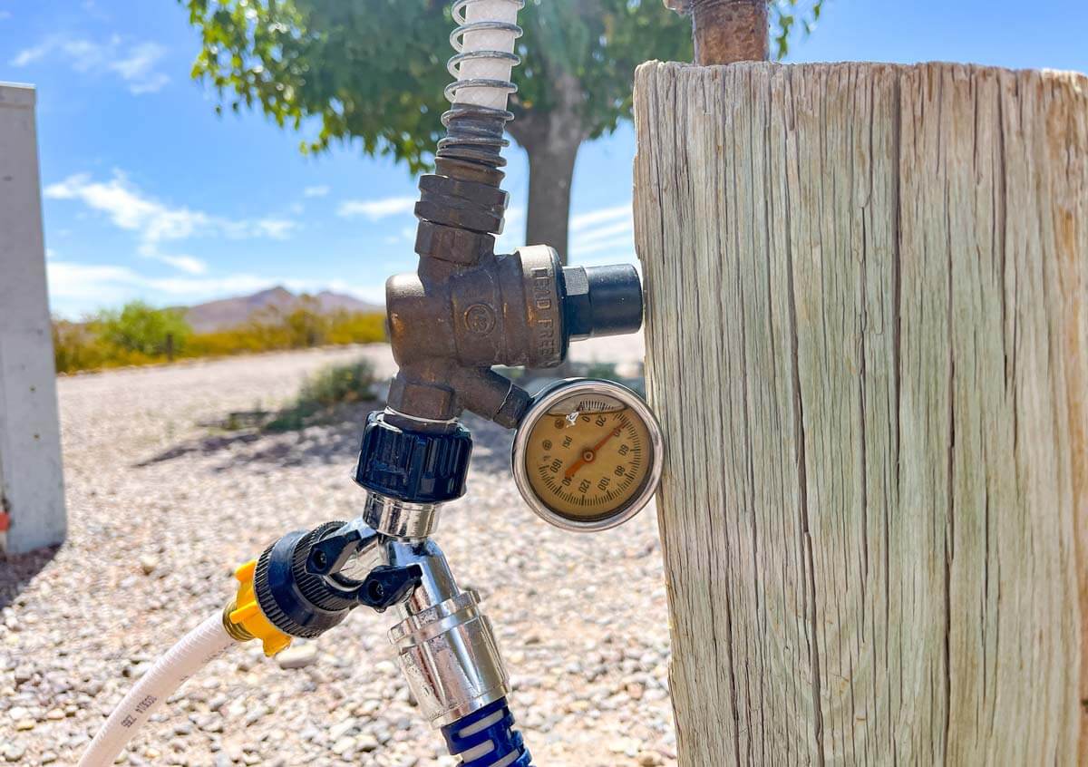 Water pressure regulator hooked to spigot and RV hoses in camping spot.