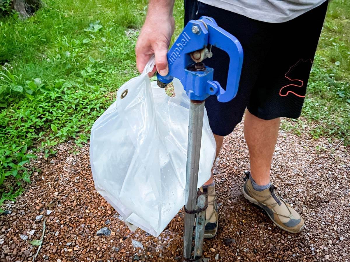 Collapsible water tote being filled at a spigot in a campground.