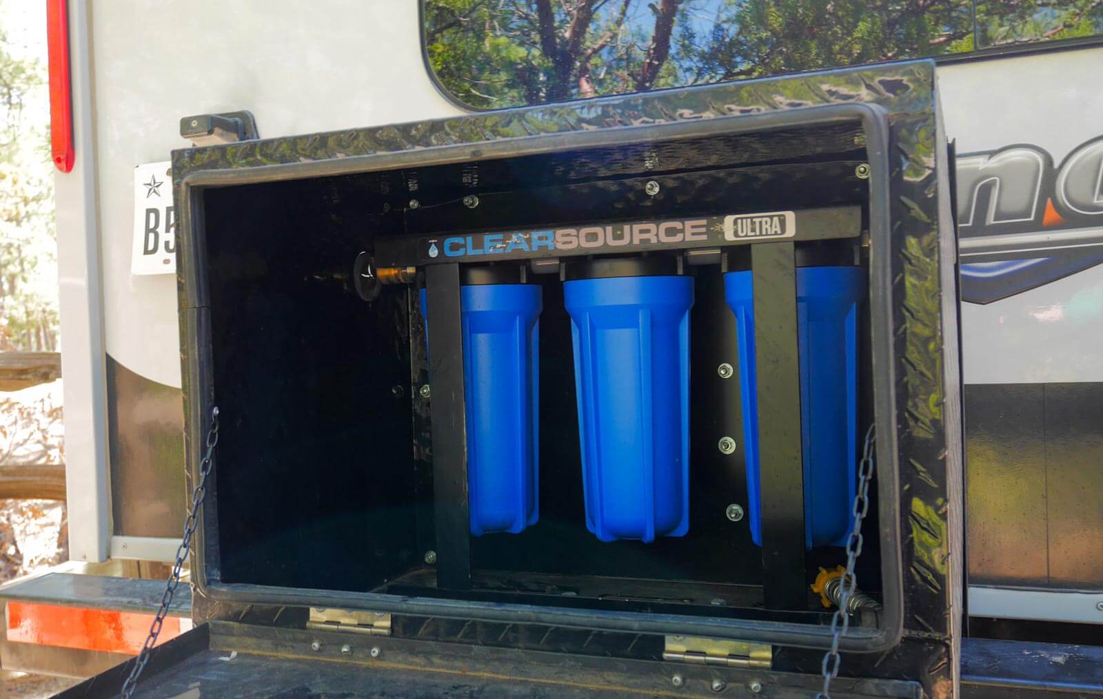 Clearsource water filter in mounted box on an RV camper bumper.