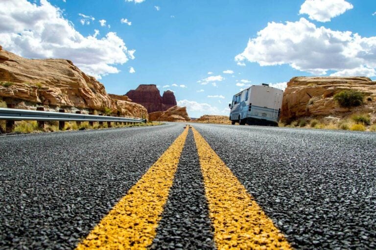 Open road in the desert with motorhome parked on the side.