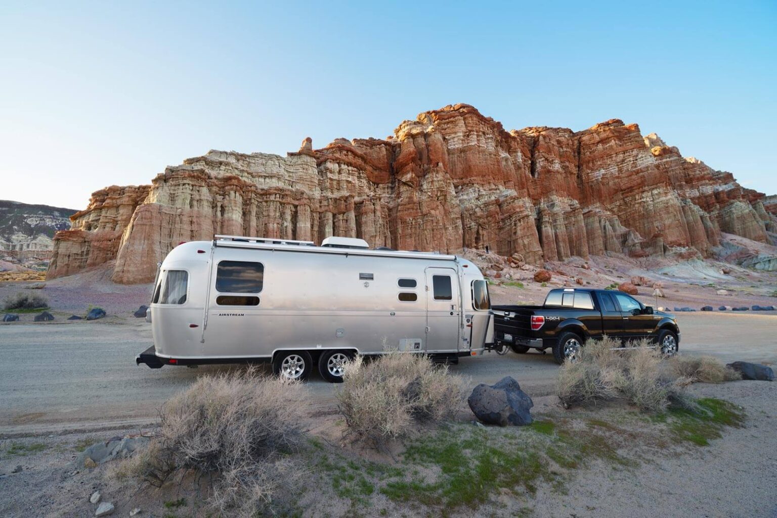 Travel trailer parked in front of desert rocks.