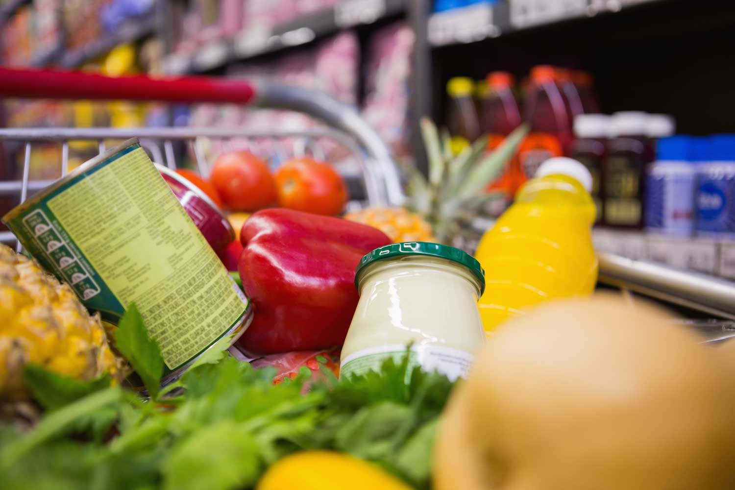 close up of groceries stacked in grocery cart