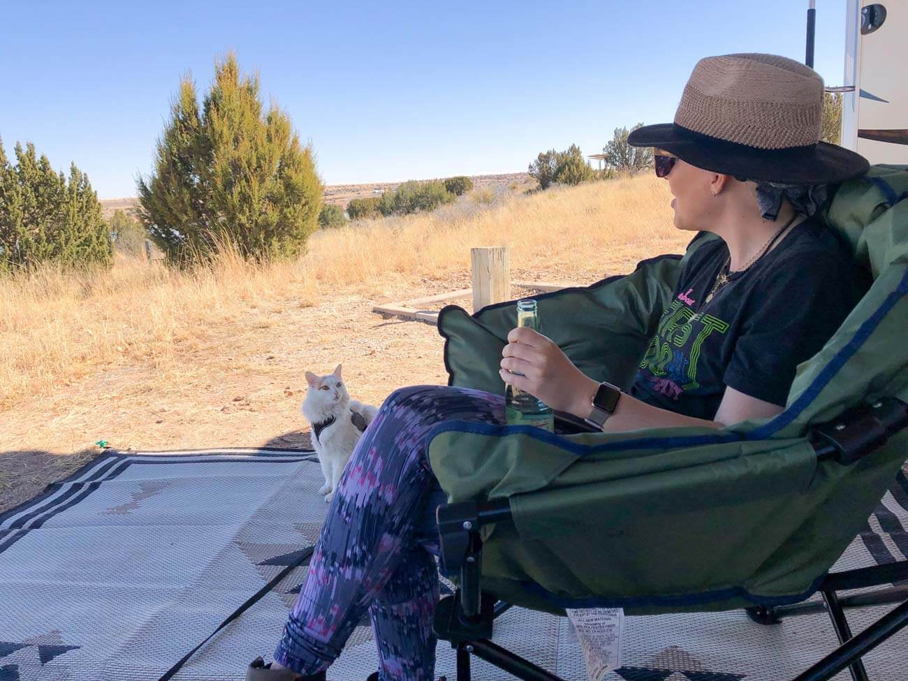 Woman sitting in camping chair outside at RV campground hanging out with cat.
