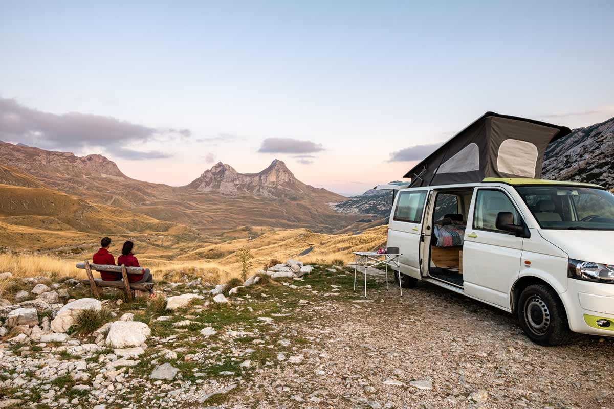 van boondocking near the mountains with couple sitting on a bench
