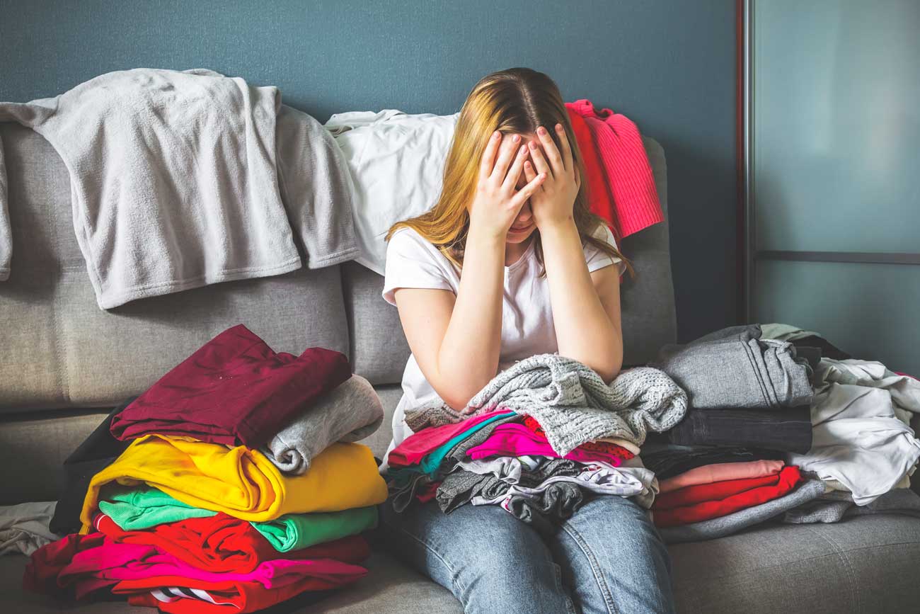 woman frustrated as she is going through decluttering clothes