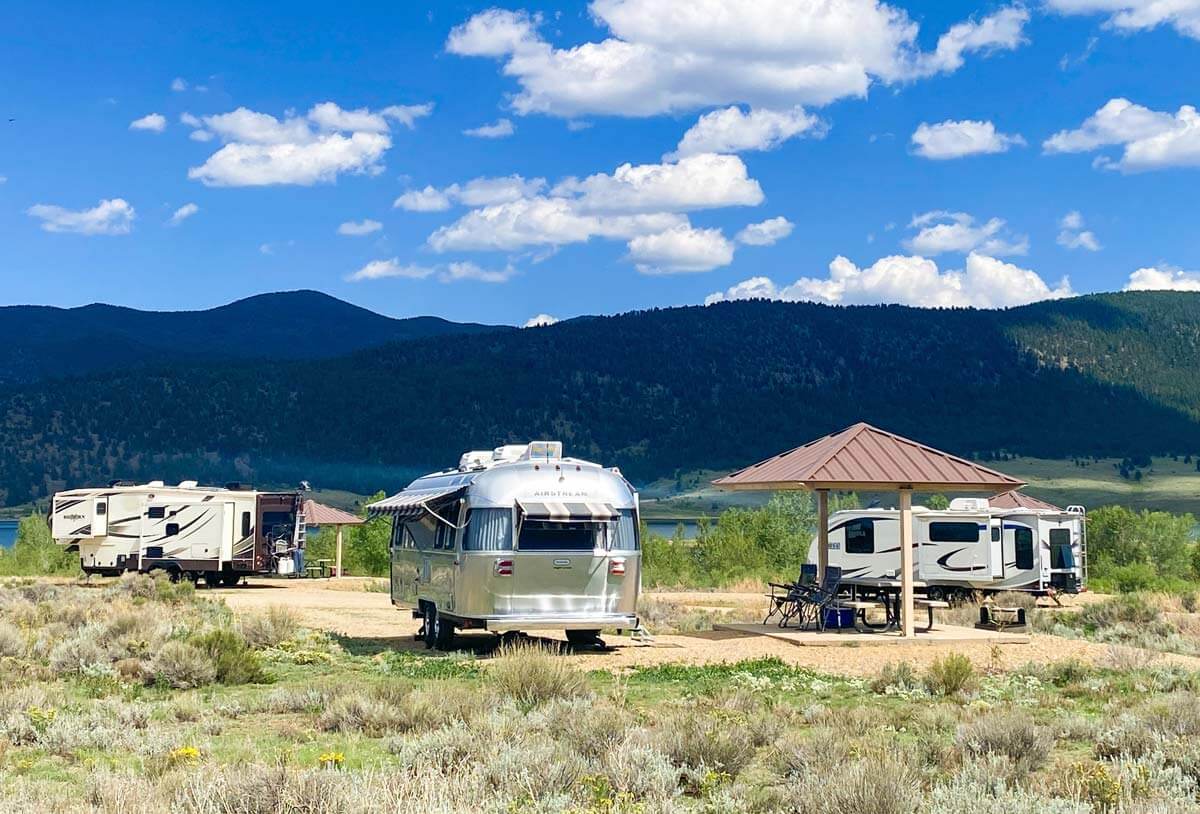 Different travel trailers parked at state park campsites in the mountains.