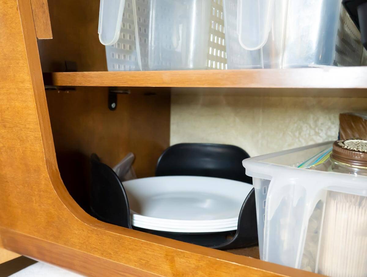 dishes in storage container in RV kitchen cabinet