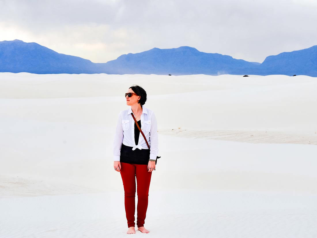 woman standing on white sand with mountains in the background at White Sands National Park 