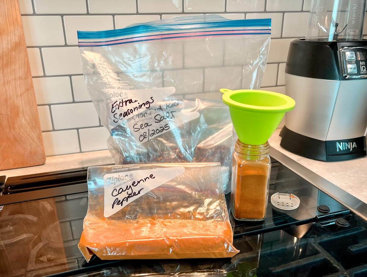 bulk spice storage in labeled plastic bags with funnel in spice jar