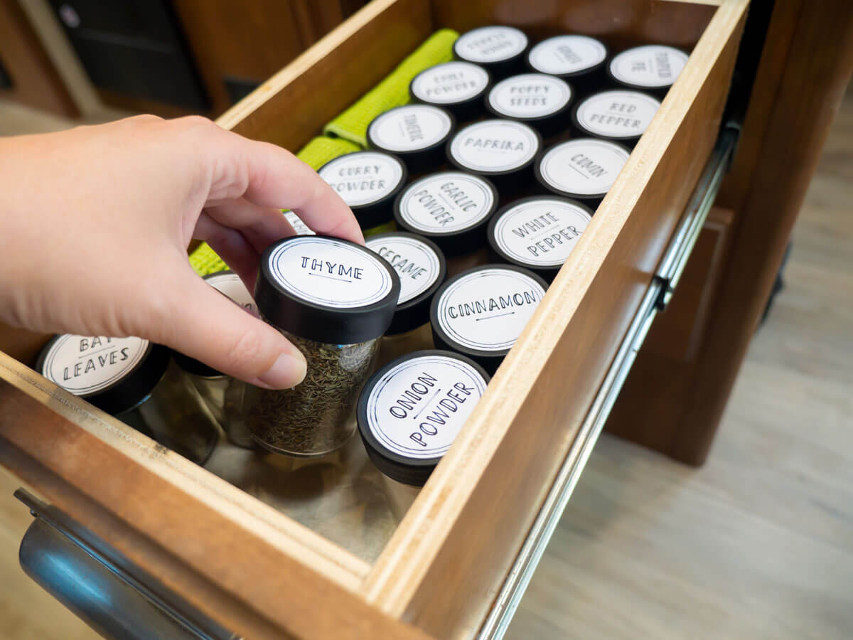 person reaching into organized spice drawer to grab spice jar