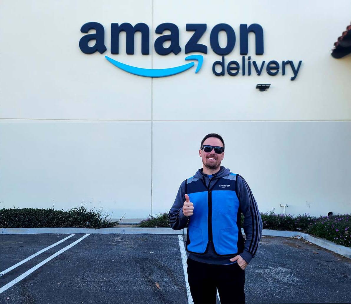Workamper in Amazon uniform in front of Amazon Delivery warehouse.