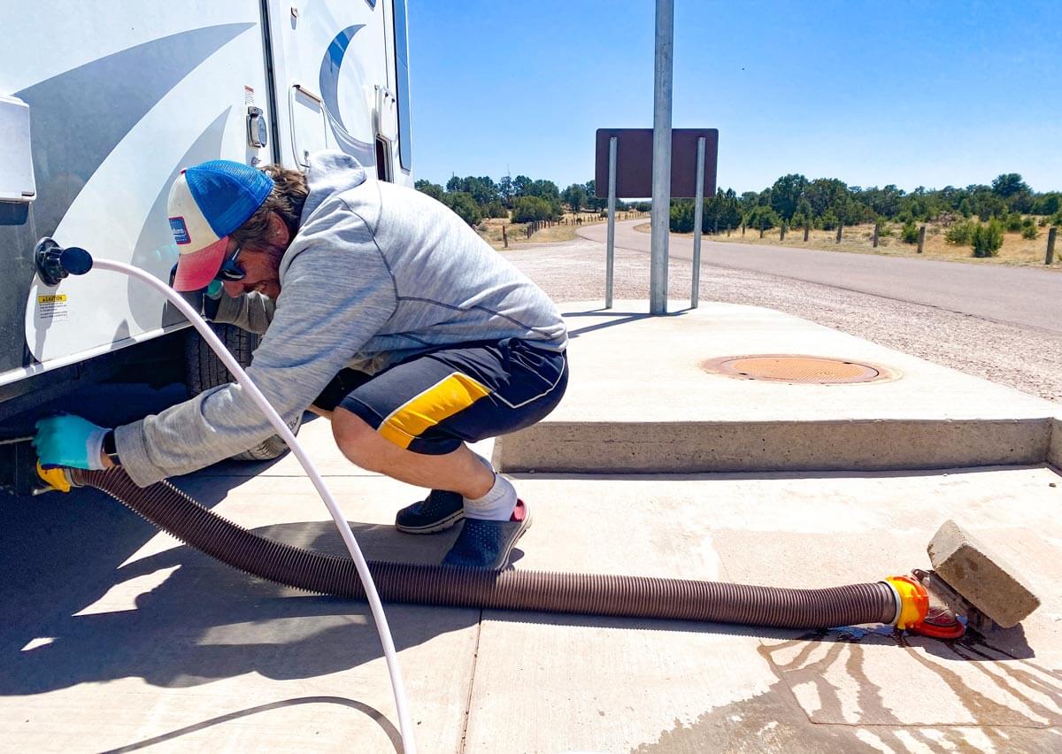 Man connecting black water sewer hose to RV.