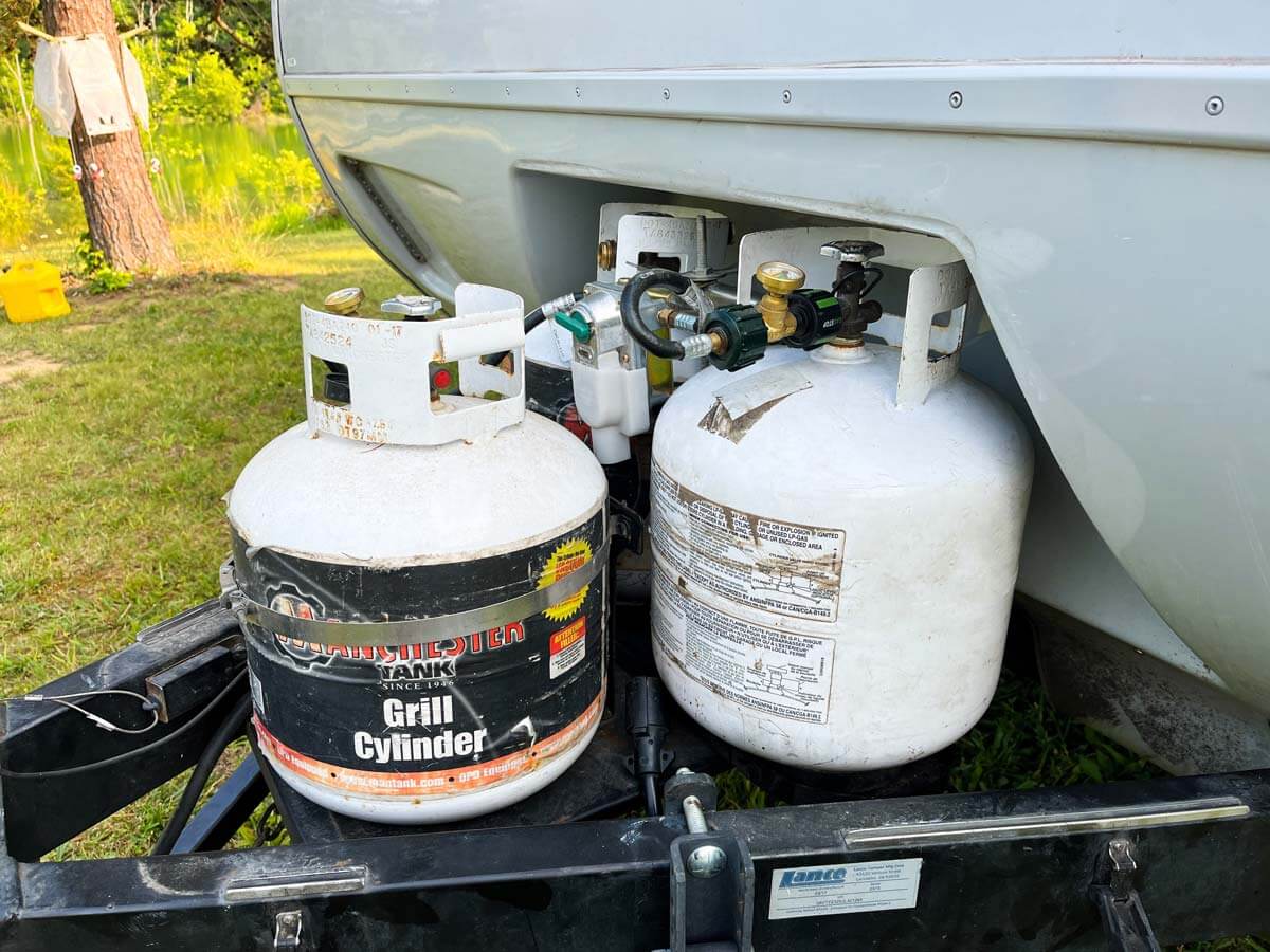 Three propane bottles mounted on the front of a travel trailer.