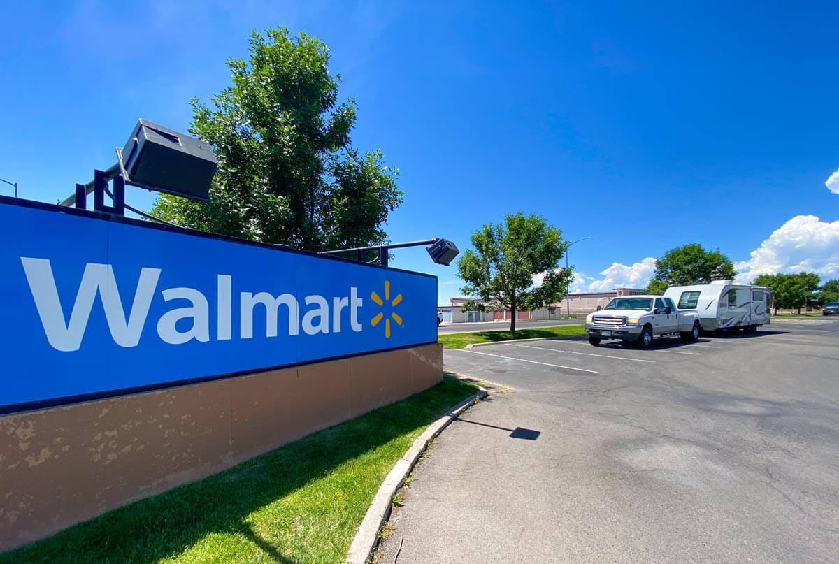 Walmart sign with RV travel trailer and tow vehicle in the parking lot.