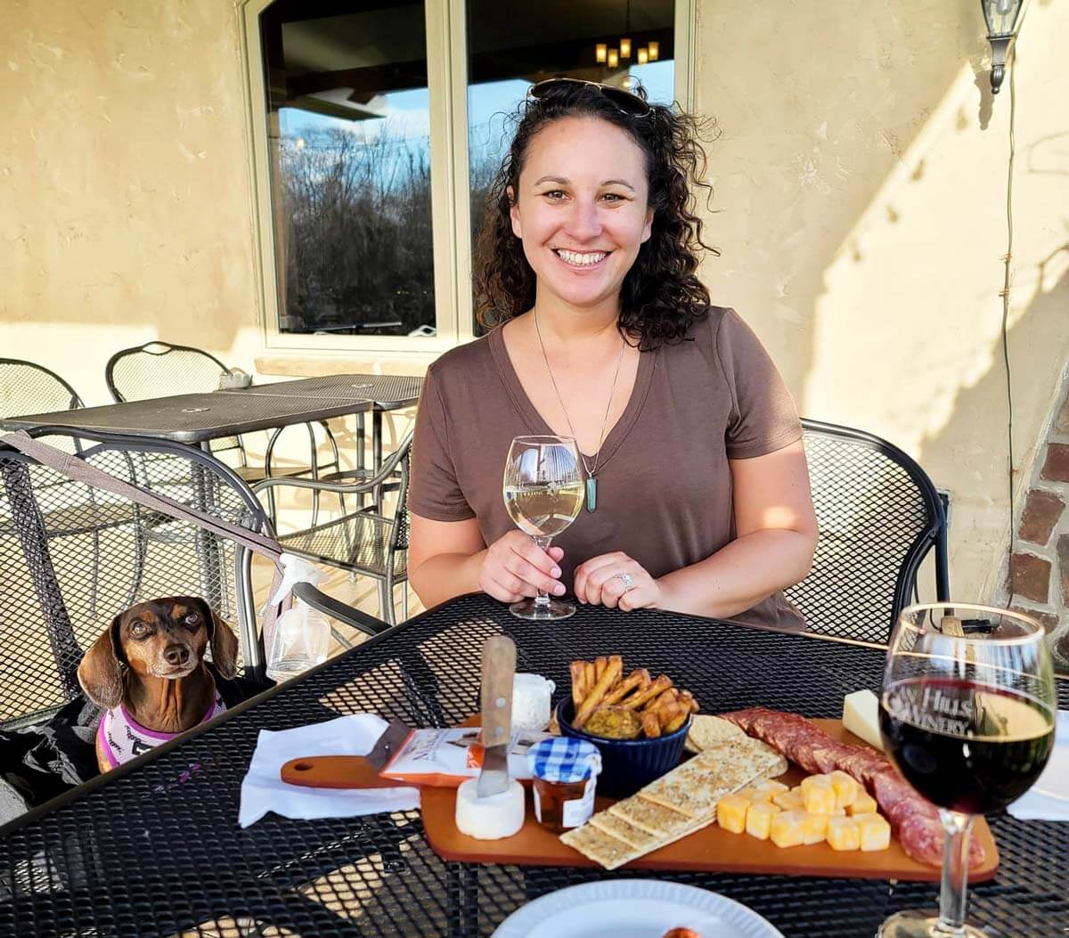 RVer enjoying a wine tasting and cheese board with her dog at a Harvest Hosts location.