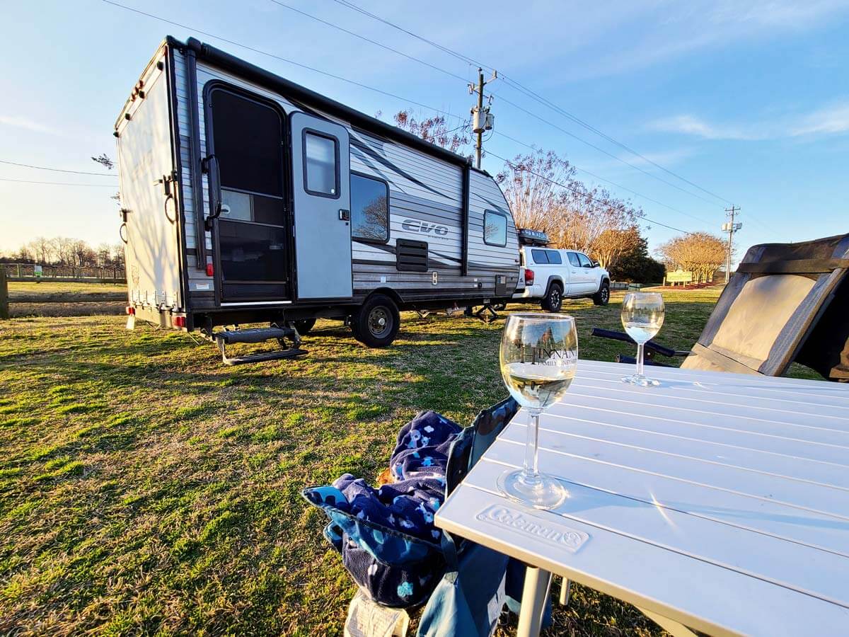 Travel trailer at Harvest Hosts with wine glasses on a picnic table outside.