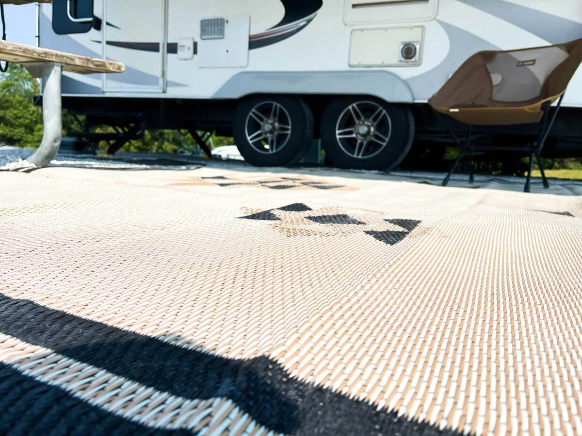 Close up of outdoor rug in front of a travel trailer.