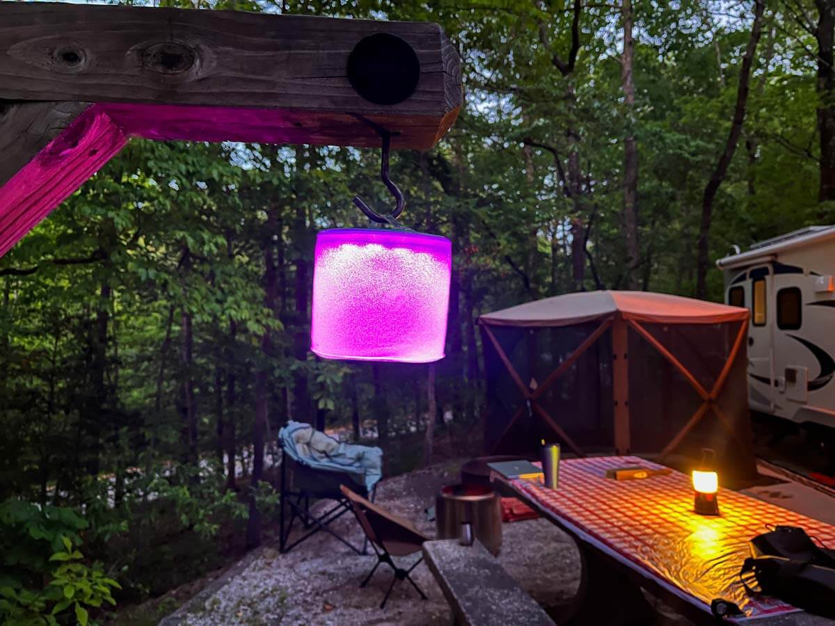 Multiple color solar light hanging from a lantern post with the RV campsite setup in the background.