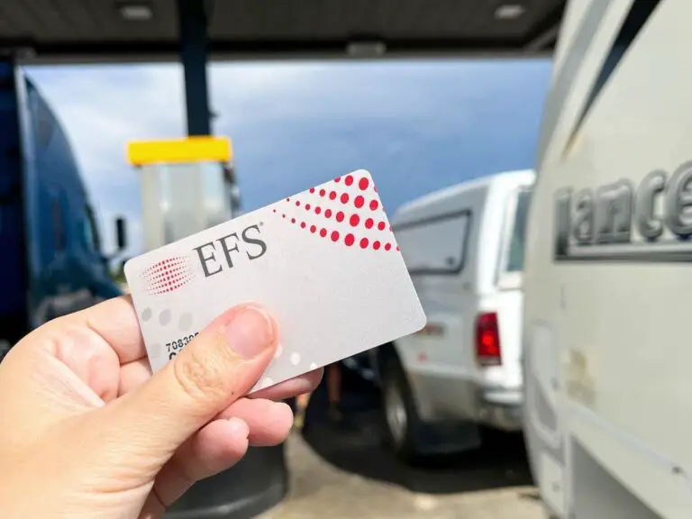 RVer holding EFS fuel card in front of a truck lane diesel pump at a truck stop.
